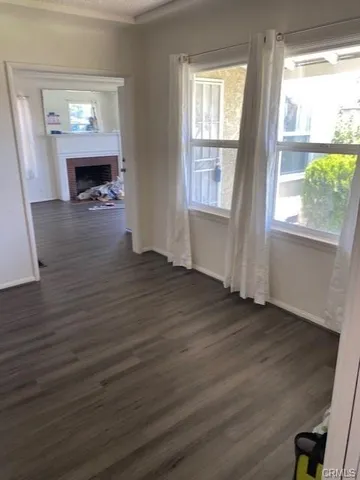 an empty room with wooden floor fireplace and windows