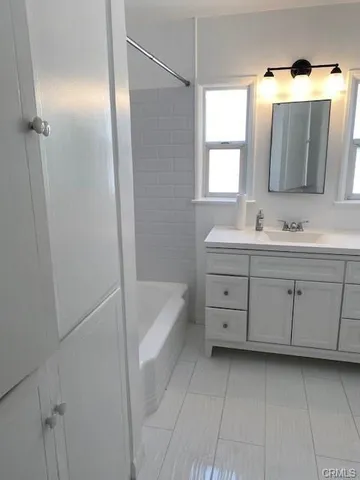 a bathroom with a double vanity sink mirror and bathtub
