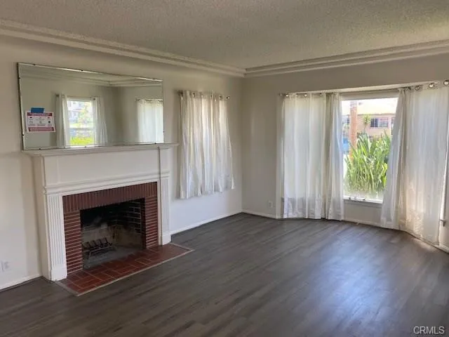 a view of an empty room with wooden floor fireplace and a window