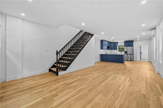 a view of an empty room with wooden floor and stairs