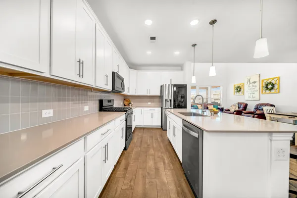 a kitchen with kitchen island granite countertop a sink a counter top space stainless steel appliances and cabinets