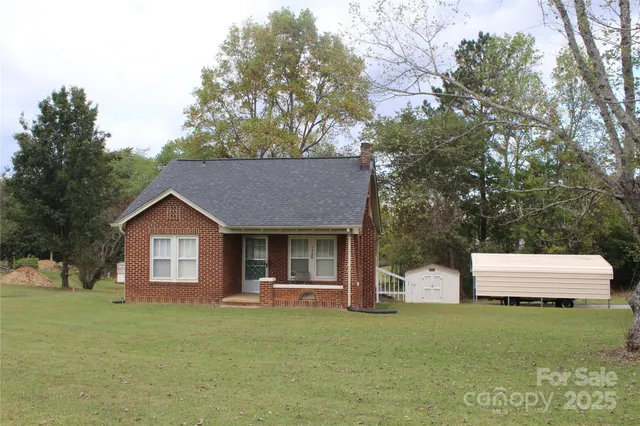 a front view of a house with a garden and tree