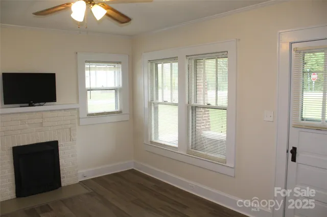 a view of a livingroom with a fireplace wooden floor and windows