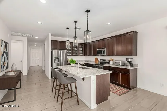 a kitchen with stainless steel appliances a stove a sink a refrigerator and chairs