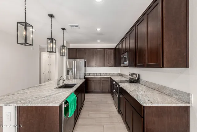 a kitchen with stainless steel appliances a stove a sink a microwave a refrigerator and cabinets