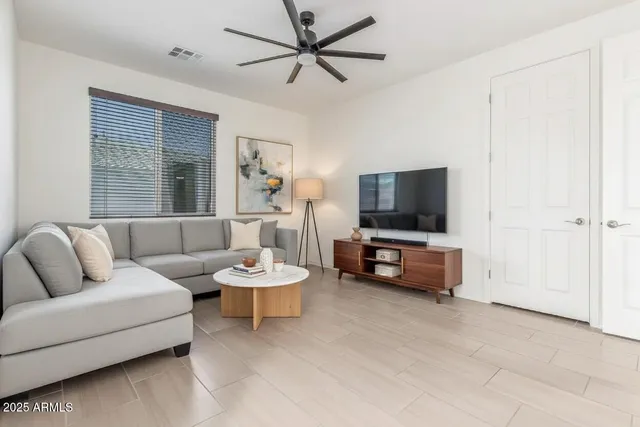 an empty room with wooden floor fan and window