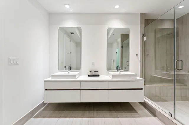 a bathroom with a double vanity sink mirror and shower