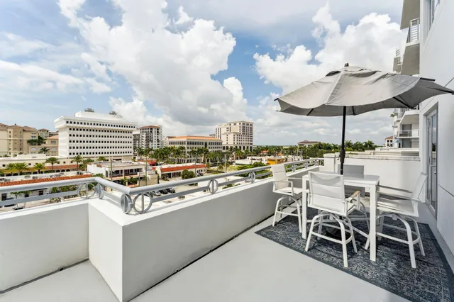 a view of a white building with a yard and potted plants