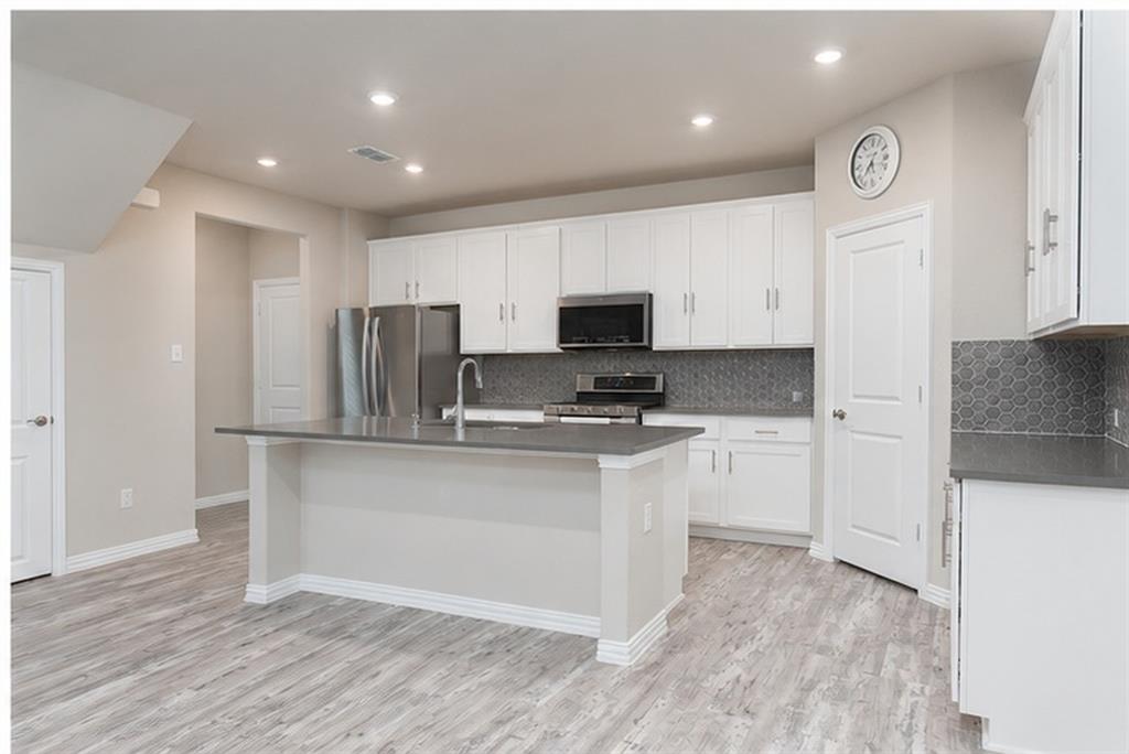 3704 Banton Street Rowlett, TX 75089 - Photo 6 of 16 Kitchen featuring a central island, stainless steel appliances, white cabinetry, dark countertops, and hexagonal tile backsplash