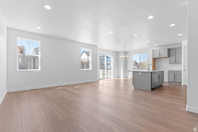 1024 South Tanner Road Santaquin, UT 84655 - Photo 9 of 20 Unfurnished living room featuring suspended lighting, light wood-style flooring, and a textured ceiling