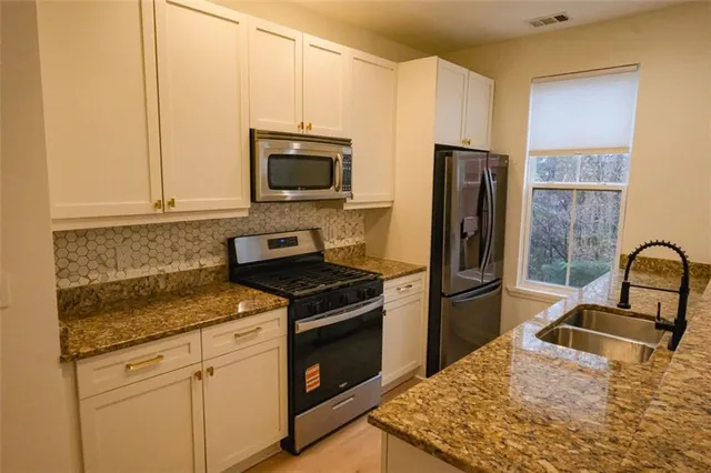 a kitchen with stainless steel appliances granite countertop a refrigerator stove top oven and sink
