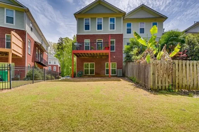 a view of a brick house next to a yard with plants and trees