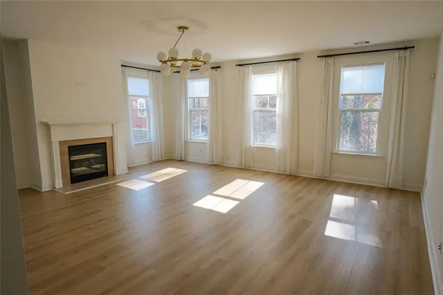 an empty room with wooden floor fireplace and windows