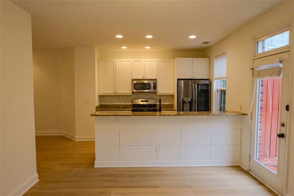 6001 Brookside Oak Circle Norcross, GA 30093 - Photo 7 of 40 a view of a kitchen with stainless steel appliances wooden floor and chair