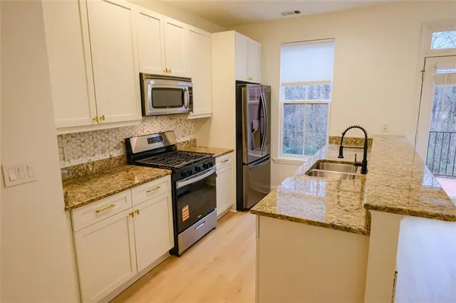 a kitchen with granite countertop a refrigerator stove and sink