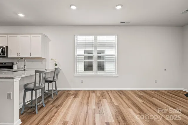 a view of kitchen and empty room with wooden floor