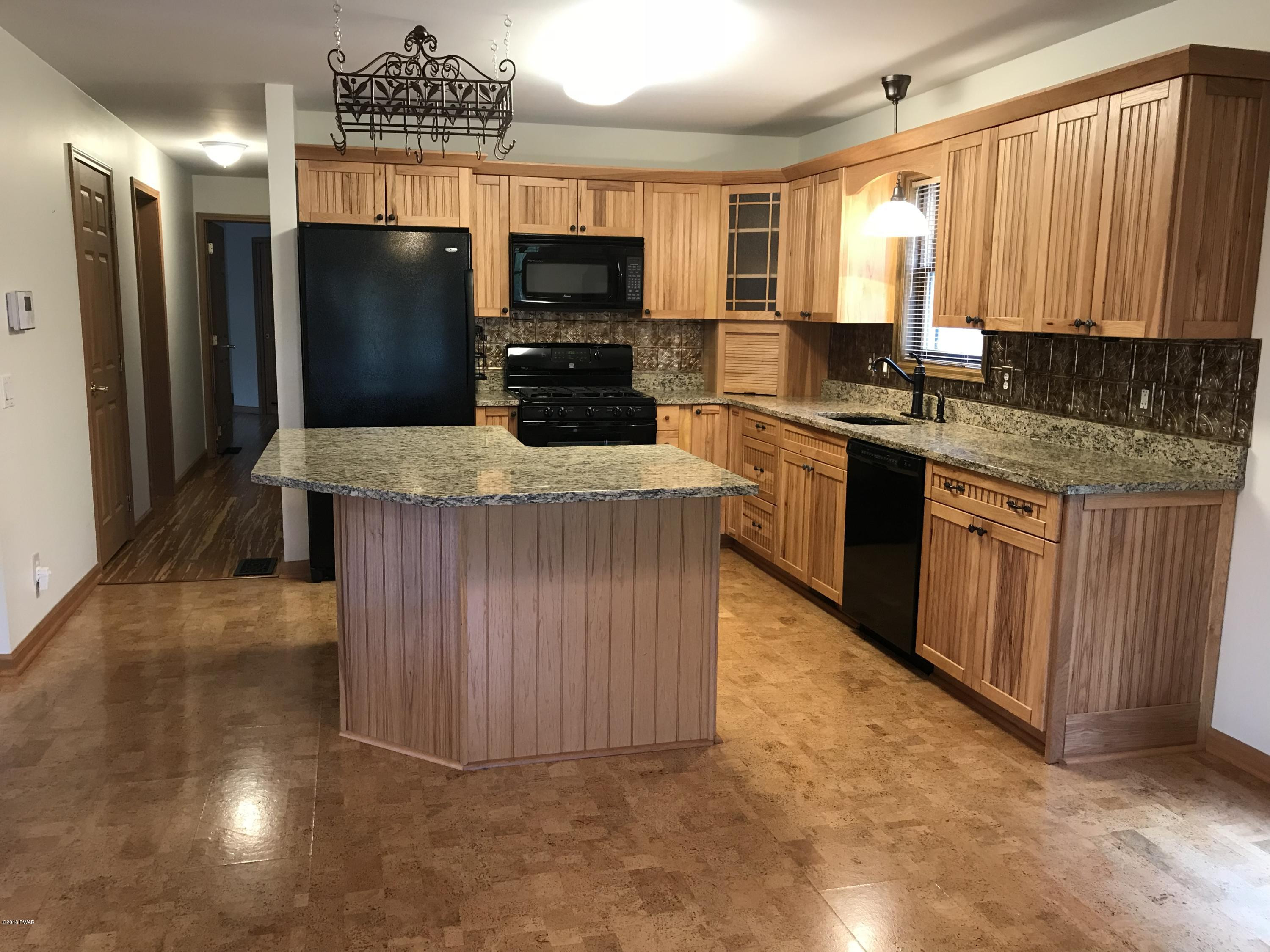232 Maple Ridge Drive Hawley, PA 18428 - Photo 8 of 44 a kitchen with kitchen island granite countertop wooden cabinets a refrigerator and a sink
