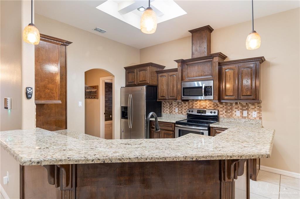 2112 Kilgore Avenue McAllen, TX 78504 - Photo 14 of 19 a kitchen with stainless steel appliances kitchen island granite countertop a refrigerator a stove and a sink