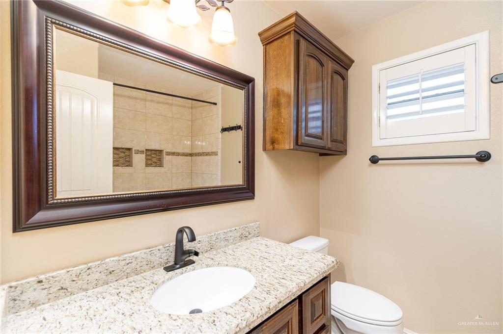 2112 Kilgore Avenue McAllen, TX 78504 - Photo 7 of 19 a bathroom with a granite countertop sink toilet and mirror