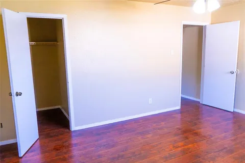 a view of an empty room with wooden floor and a hallway