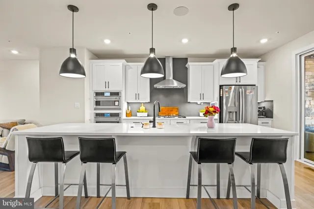 a kitchen with stainless steel appliances a dining table chairs and white cabinets