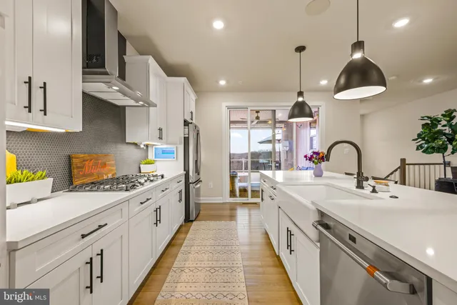 a large kitchen with stainless steel appliances granite countertop a sink a stove and a wooden floors