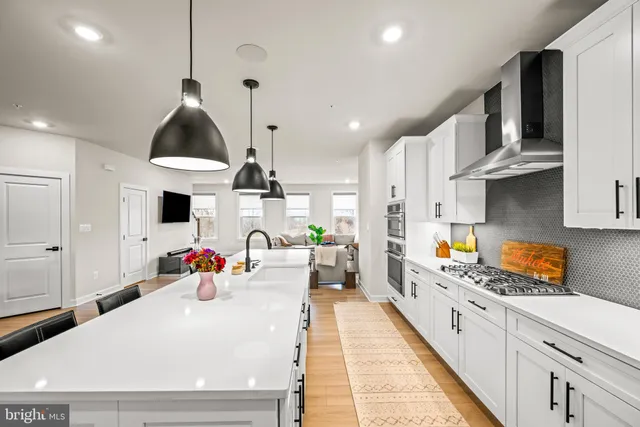a kitchen with stainless steel appliances a sink a stove a chimney a refrigerator and cabinets