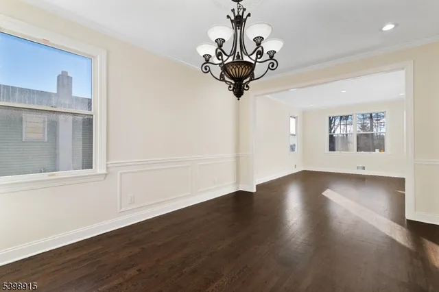 a view of a room with wooden floor chandelier and windows
