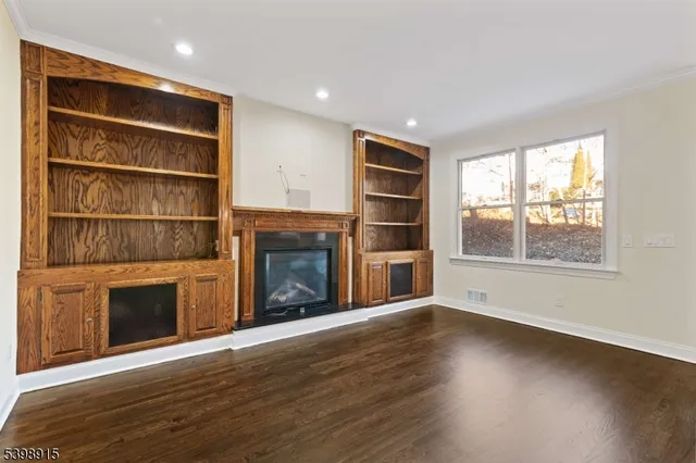 a view of an empty room with wooden floor fireplace and a window