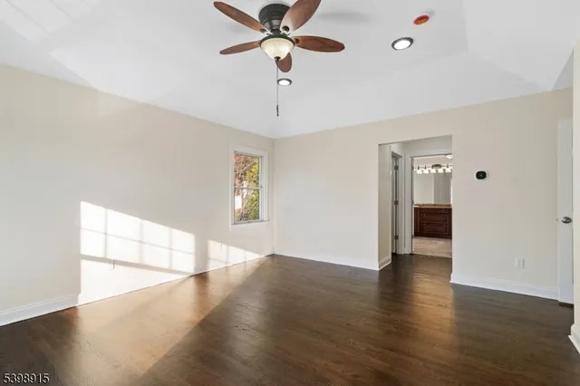 a view of an empty room with window and wooden floor