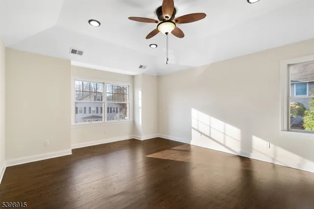 a view of an empty room with window and wooden floor