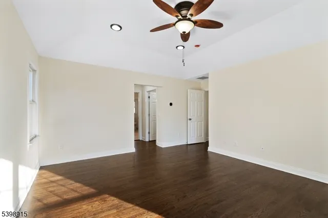 an empty room with wooden floor fan and windows