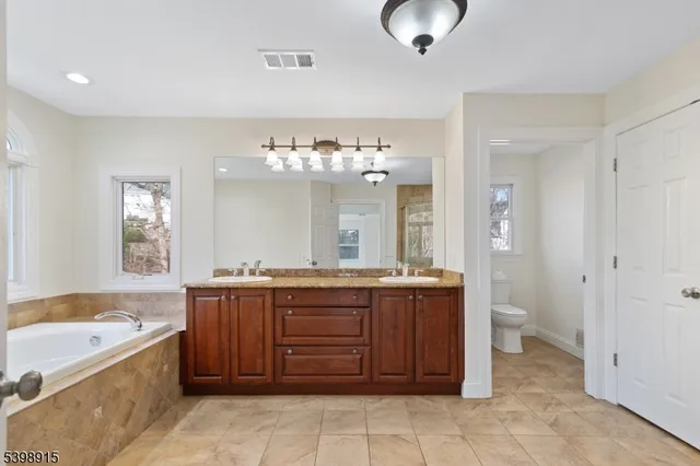 a spacious bathroom with a granite countertop sink and a bathtub