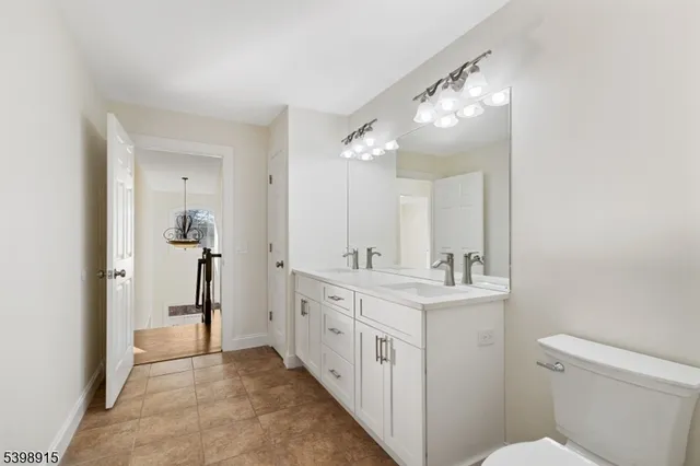 a bathroom with a double vanity sink toilet and a mirror