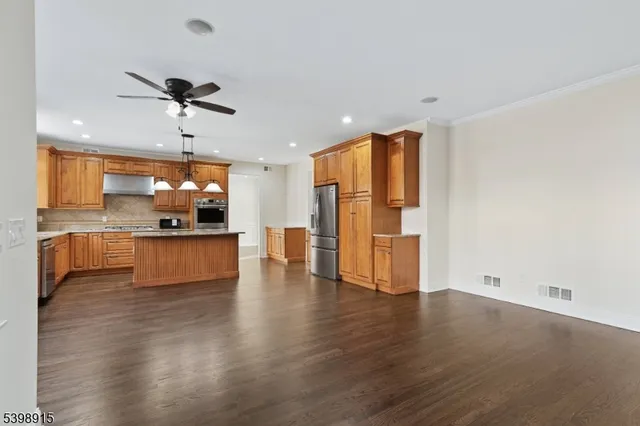 a view of kitchen with stainless steel appliances wooden floor and a large window