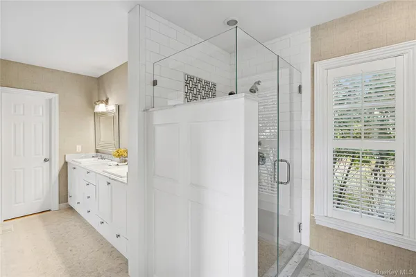 a spacious bathroom with a double vanity sink a large mirror and a shower