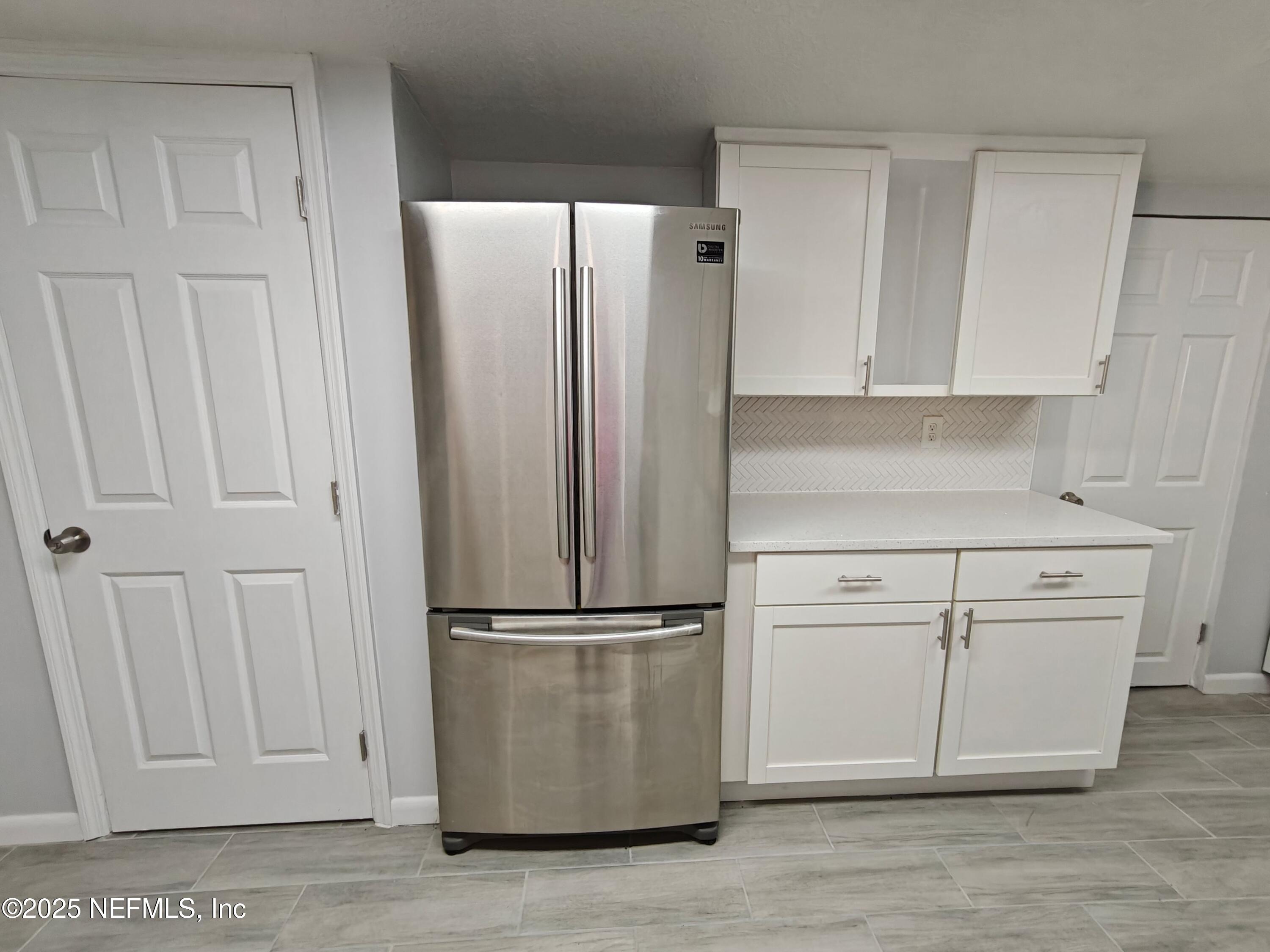 2921 Mansion Road Jacksonville, FL 32277 - Photo 17 of 40 a kitchen with a refrigerator and white cabinets