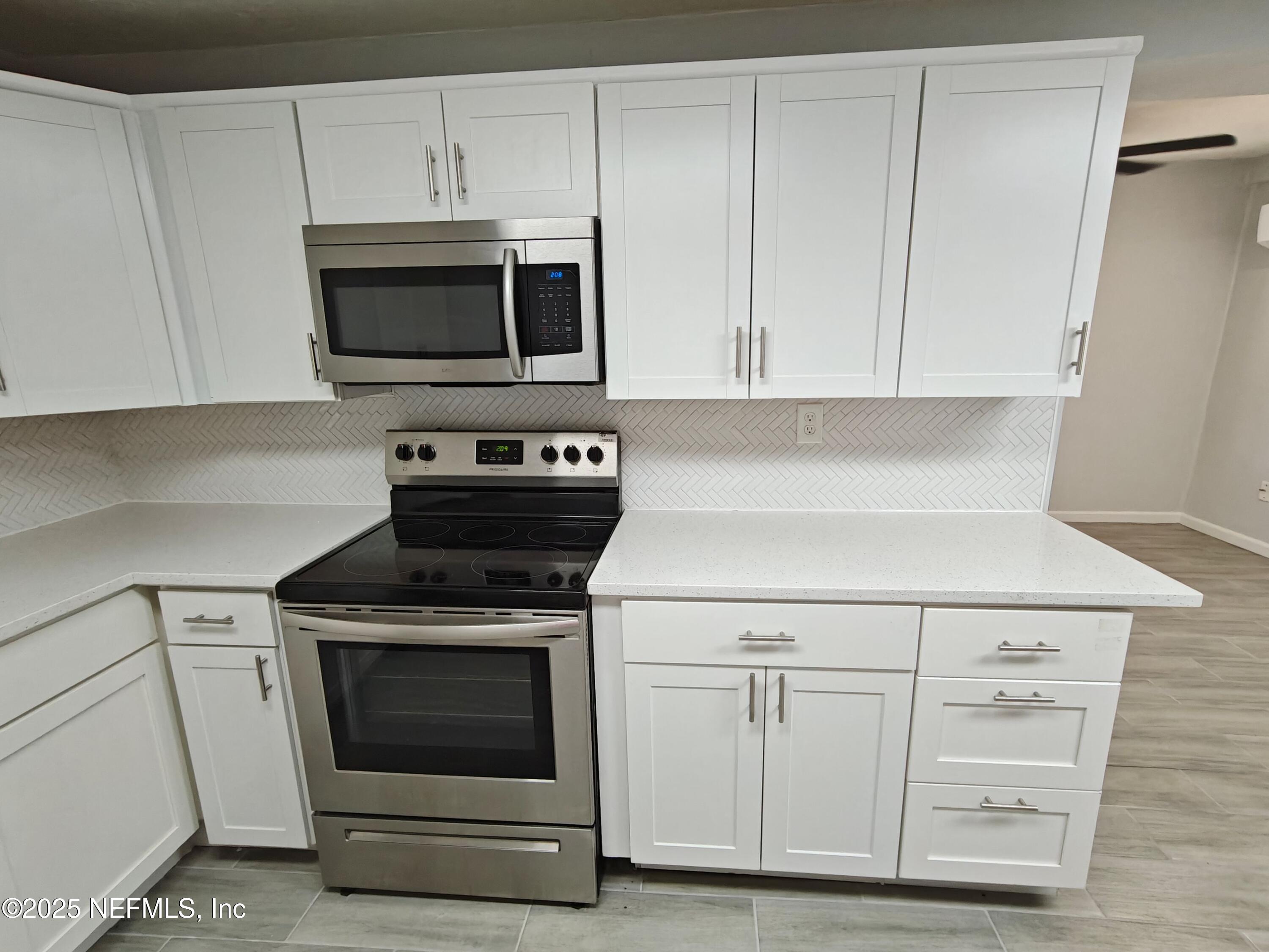 2921 Mansion Road Jacksonville, FL 32277 - Photo 18 of 40 a kitchen with white cabinets and appliances
