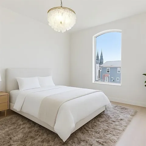 a bedroom with a large bed and a chandelier