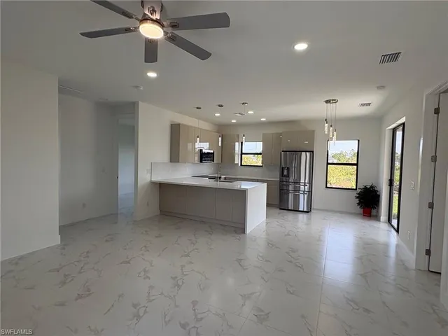 an empty room with a kitchen and a ceiling fan