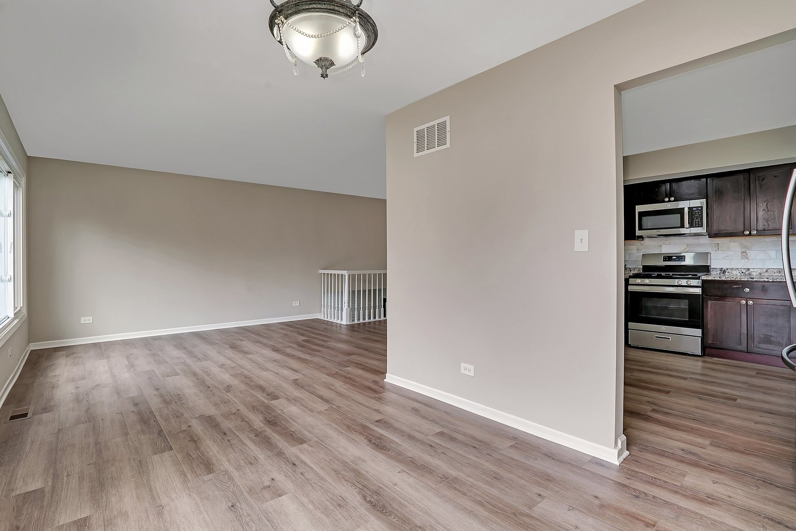 161 South Schmidt Road Bolingbrook, IL 60440 - Photo 6 of 26 an empty room with wooden floor cabinet and a kitchen view