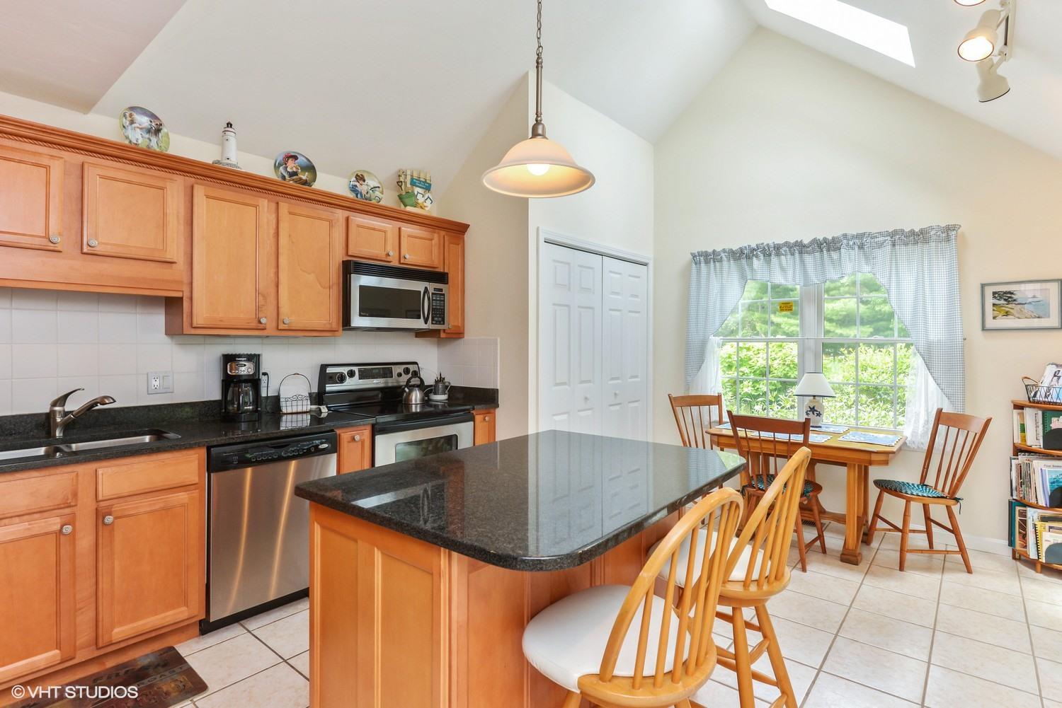23 Gold Leaf Lane Mashpee, MA 02649 - Photo 7 of 15 a kitchen with stainless steel appliances granite countertop a stove top oven a sink a dining table and chairs with wooden floor