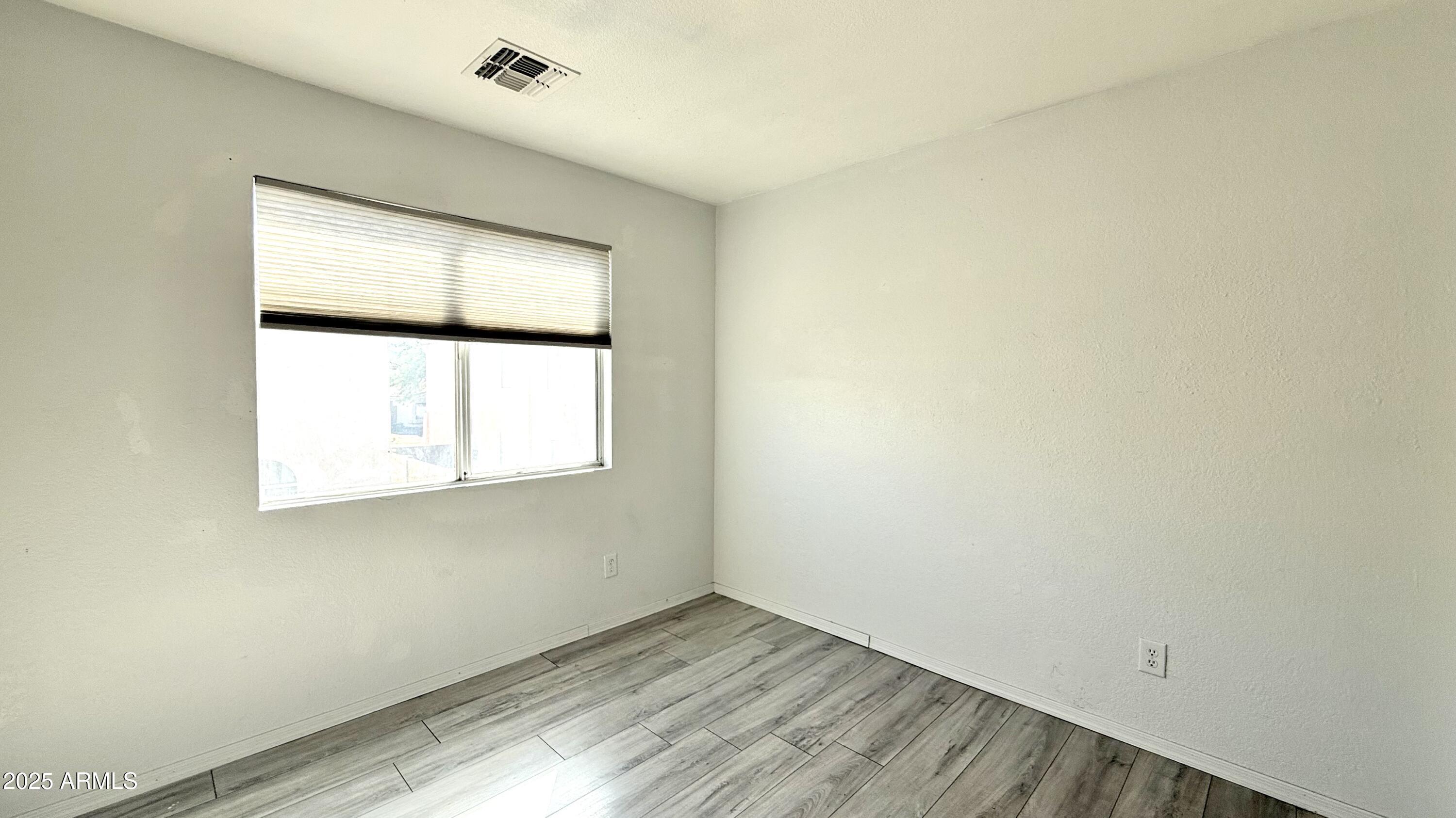 1103 East Grove Street Phoenix, AZ 85040 - Photo 11 of 21 an empty room with wooden floor and windows