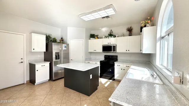 a kitchen with stainless steel appliances kitchen island granite countertop a refrigerator and a stove top oven