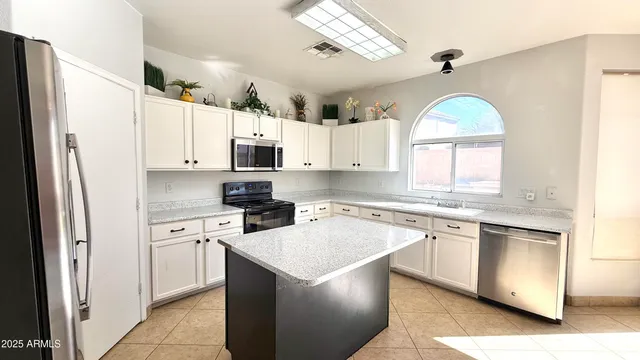 a kitchen with stainless steel appliances granite countertop a stove a sink dishwasher a refrigerator and white cabinets with wooden floor