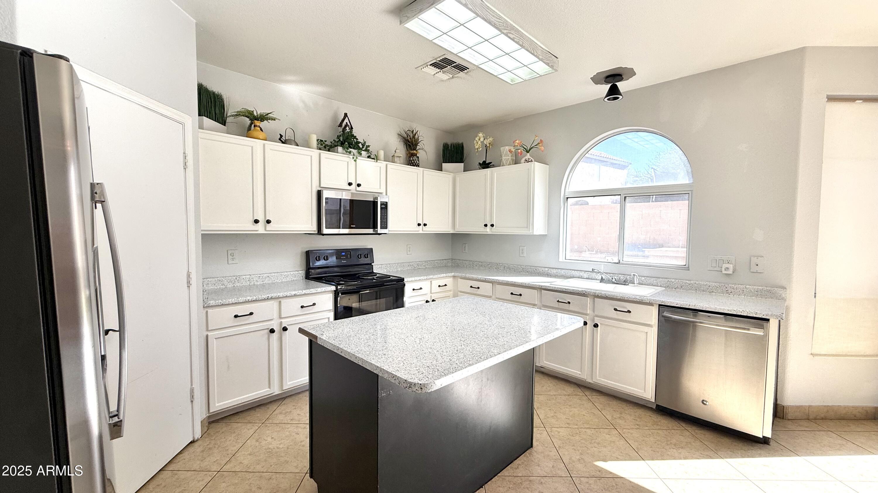 1103 East Grove Street Phoenix, AZ 85040 - Photo 4 of 21 a kitchen with stainless steel appliances granite countertop a stove a sink dishwasher a refrigerator and white cabinets with wooden floor