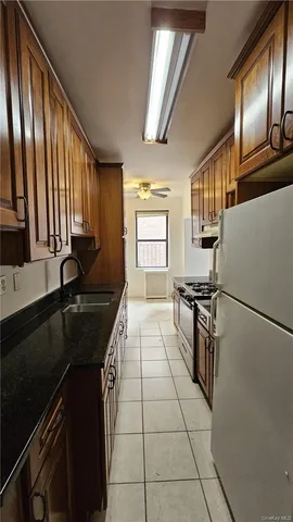 a kitchen with granite countertop stainless steel appliances a sink stove refrigerator and cabinets