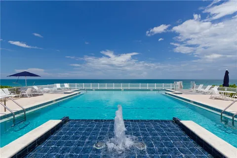 a view of a pool with lawn chairs under an umbrella