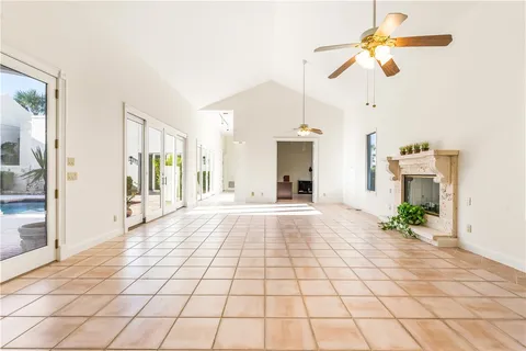 a view of an empty room and chandelier fan and kitchen view