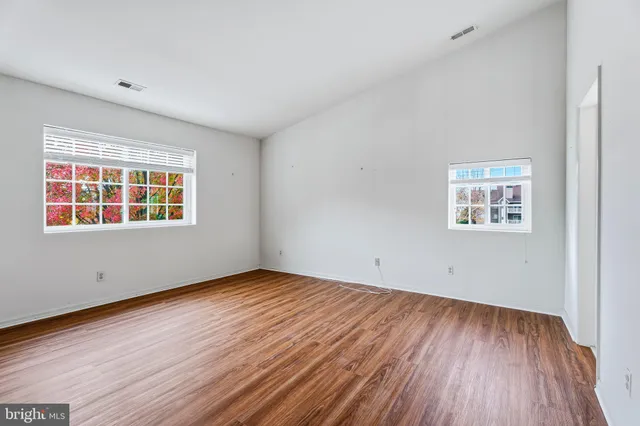 an empty room with wooden floor and windows